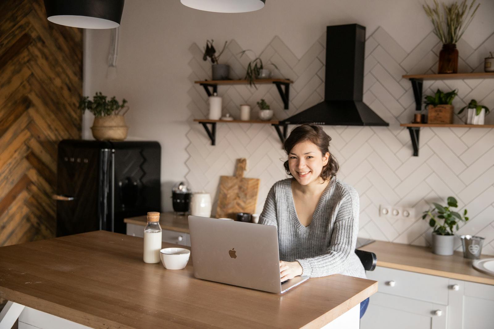 An adult in their 30s smiling at home in a bright kitchen, reflecting supported living and everyday independence